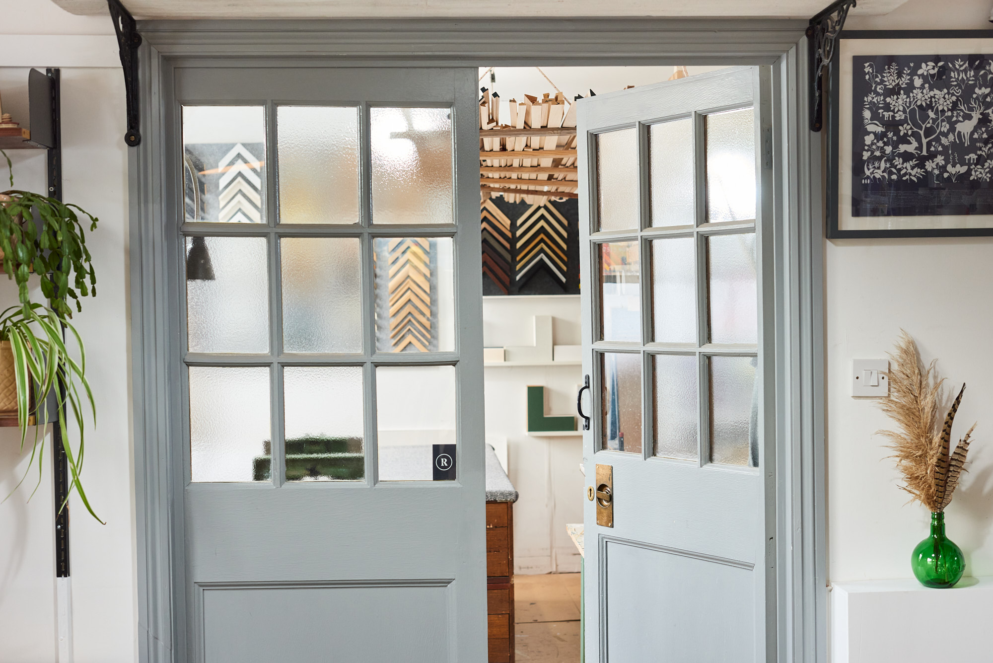 photograph of grey panelled double doors with homewares and plants in foreground and framing workshop in background